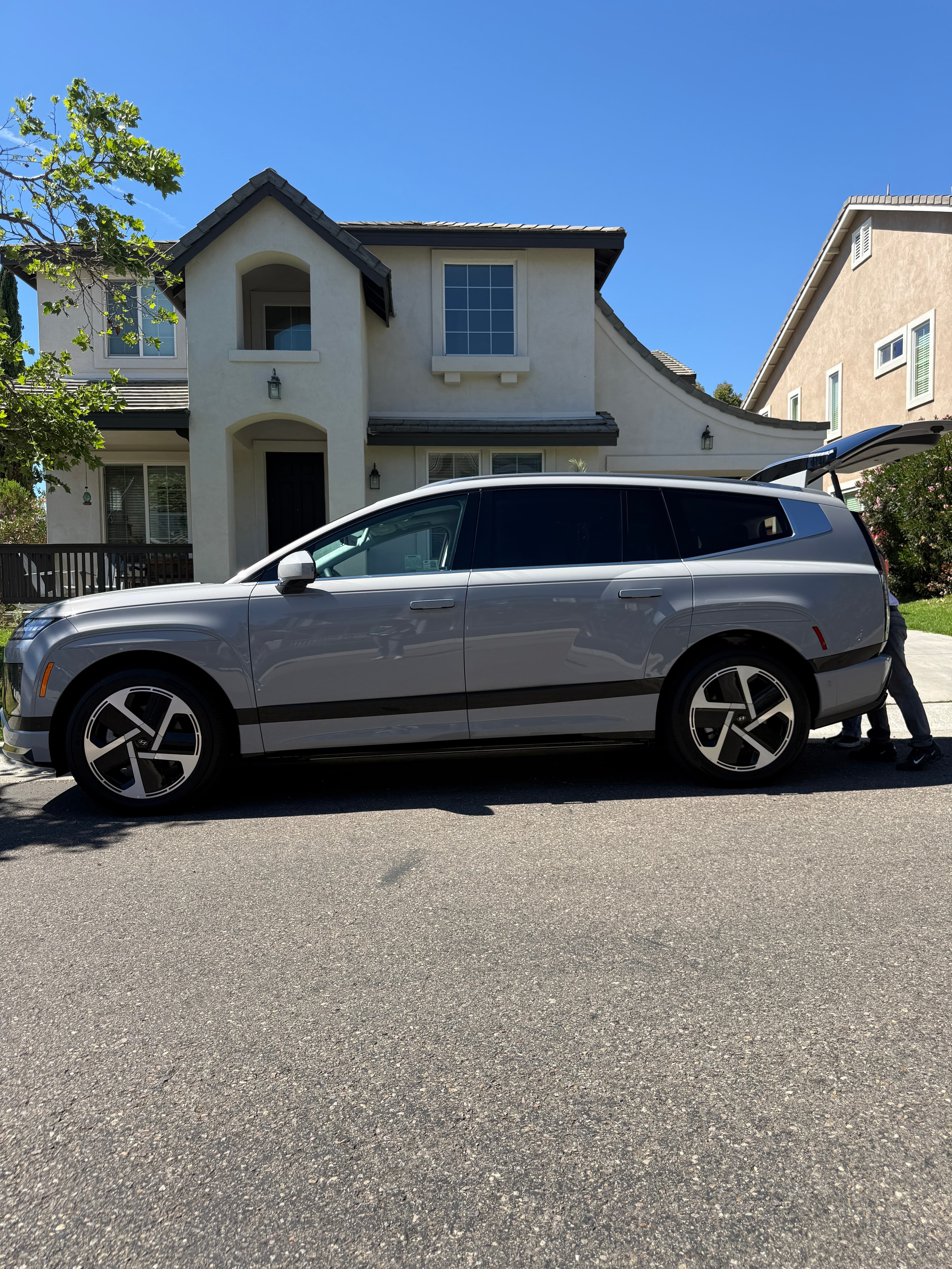 A silver Hyundai IONIQ 9 outside a client's home in San Diego, tailgate open after delivery
