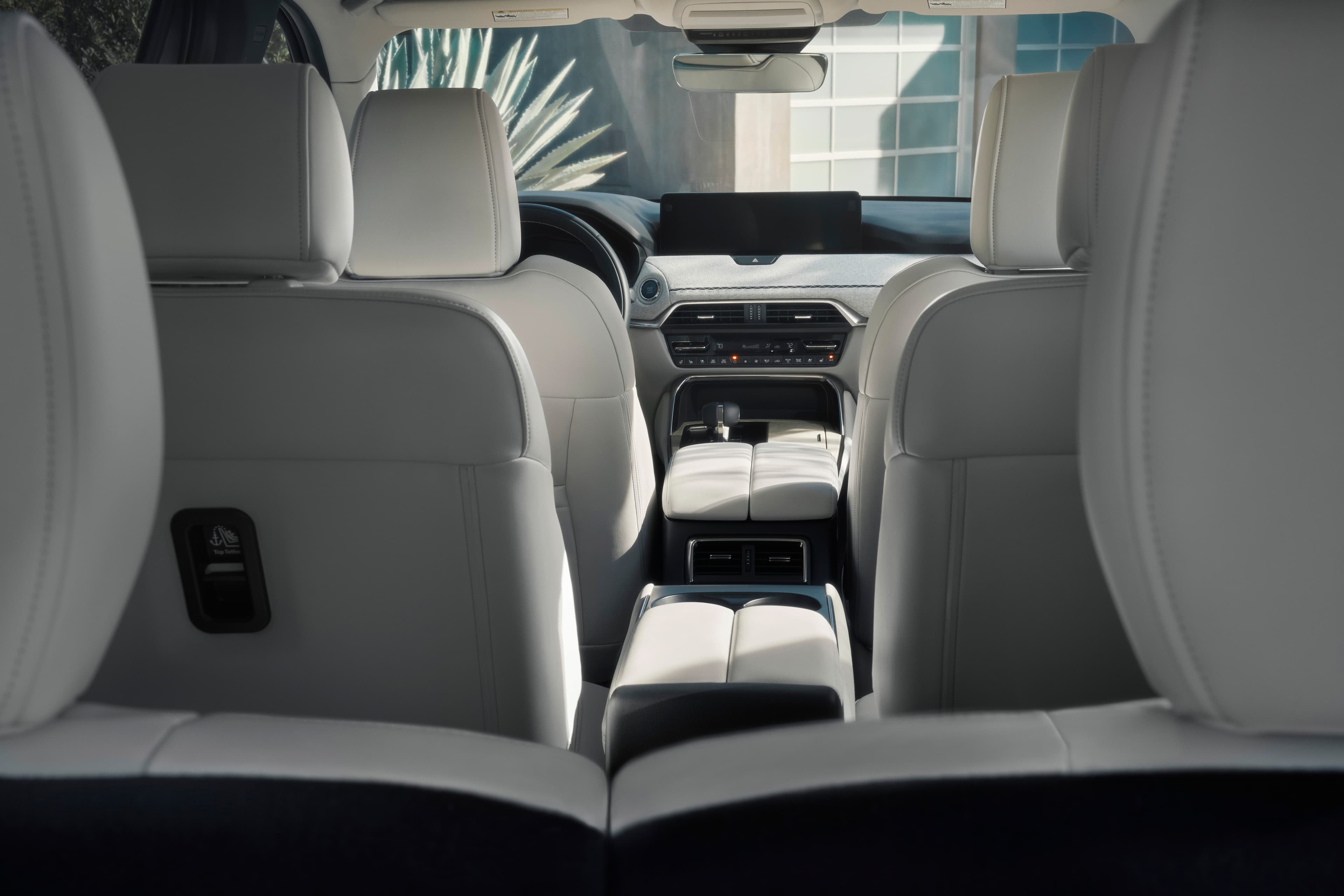 The CX-90's second-row captain's chairs seen from the third row, looking forward to the dashboard.