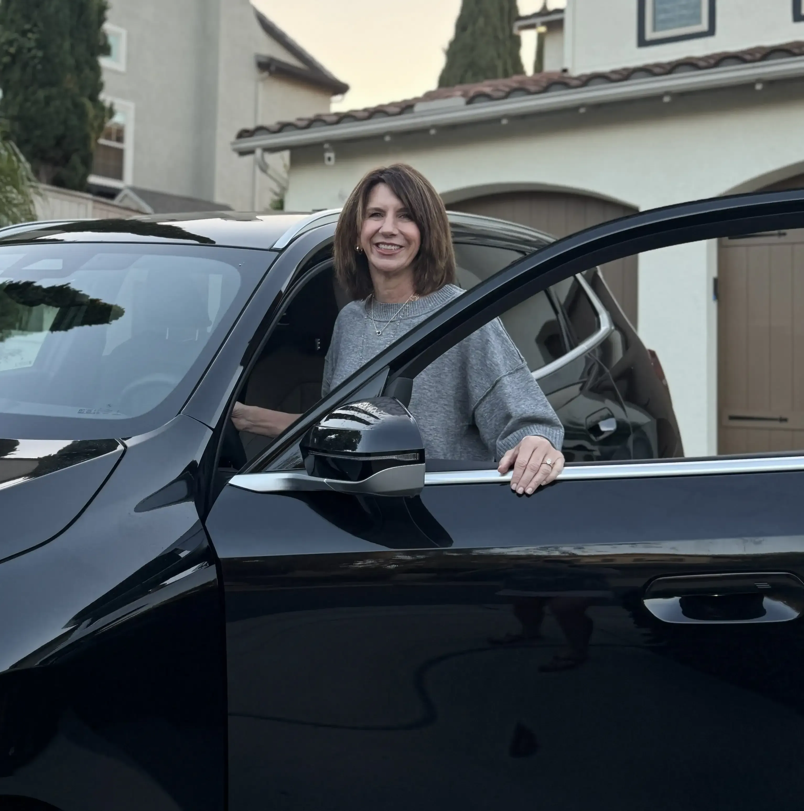 Andrea Nanigian, Co-Founder of CarOracle, at the open door of a black SUV